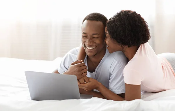 Ρομαντικός μαύρος άντρας και γυναίκα που χρησιμοποιούν φορητό υπολογιστή στο κρεβάτι — Φωτογραφία Αρχείου