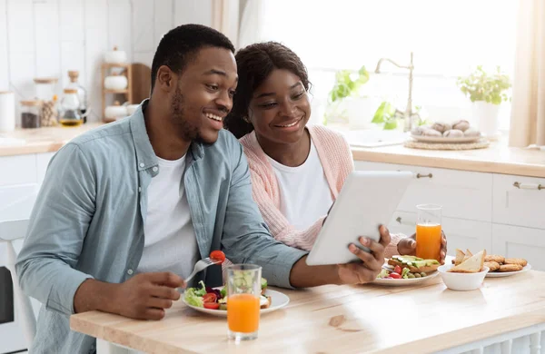 Fröhliches schwarzes Paar beim Frühstück mit digitalem Tablet in der Küche — Stockfoto