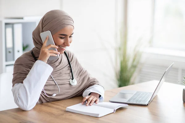 Smiling female doctor arranging appointment on phone