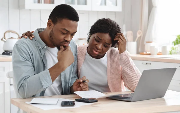 Casal negro estressado calculando orçamento familiar na cozinha, sofrendo crise financeira — Fotografia de Stock