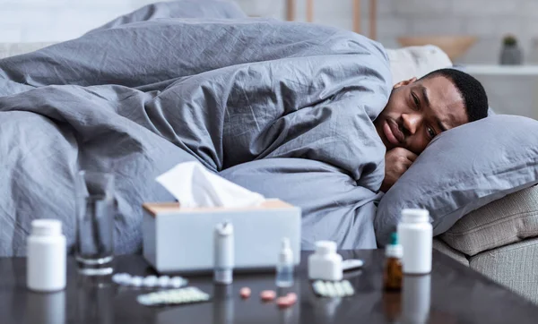 Hasta siyah adam, evinde kanepede yatarken ürperiyor. — Stok fotoğraf