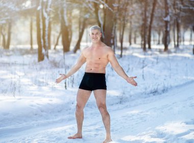Full length portrait of senior man exposing himself to cold weather, standing in underwear at frosty snowy forest clipart