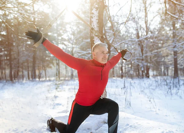 TRX suspension training concept. Athletic senior man working out with sports equipment on snowy winter day at park — Stock Photo, Image