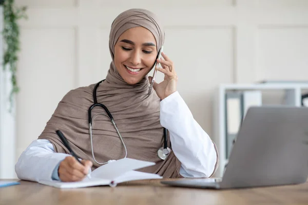 Feliz mujer musulmana médico tener conversación por teléfono con el paciente —  Fotos de Stock