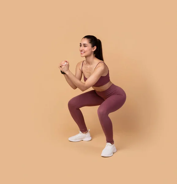 Uśmiechnięta młoda kobieta robi głębokie Squat ćwiczenia — Zdjęcie stockowe
