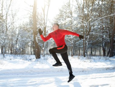 Güneşli kış parkında koşan güçlü olgun sporcunun tam boy portresi. Mevsimlik spor ve aktiviteler