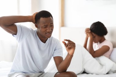 Kafası karışmış siyah adam elindeki hapa bakıyor.