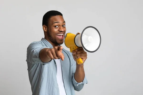 Pozitivní africký chlap křičí v megafonu přes šedé pozadí — Stock fotografie