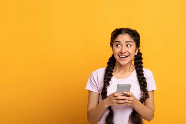 Indiase vrouw met behulp van smart phone geïsoleerd op gele achtergrond — Stockfoto