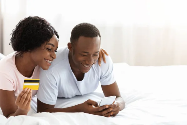 Homem negro alegre e mulher com cartão de crédito e smartphone — Fotografia de Stock