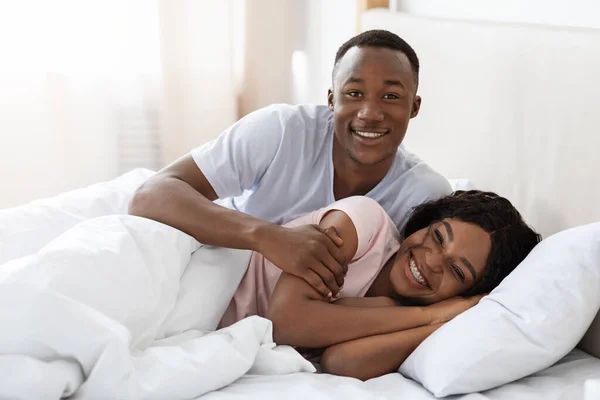 Feliz pareja negra abrazándose en la cama en casa — Foto de Stock