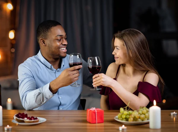 Liefdevol gemengd paar met romantisch diner in restaurant, wijn drinken en glimlachen — Stockfoto