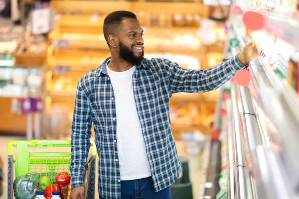 African Male Doing Shopping Standing Near Shelf In Groceries Store
