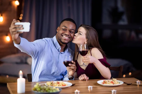 Birbirlerine aşık çok ırklı çiftler restoranda romantik bir akşam yemeği yerken selfie çekiyorlar. — Stok fotoğraf