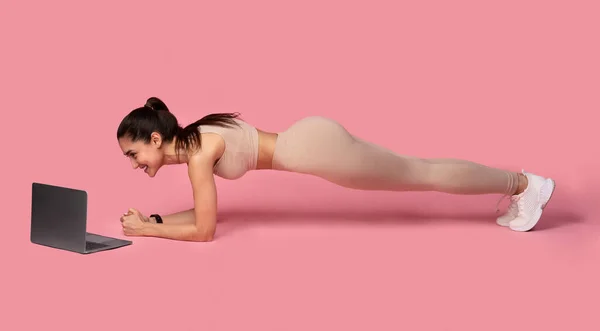 Sportliche Frau macht Plank-Tutorial am Laptop — Stockfoto