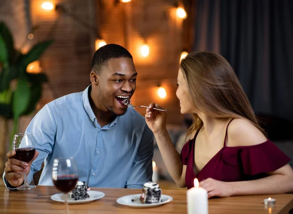 Γλυκές στιγμές. Διαφυλετικό ζευγάρι έχοντας διασκέδαση κατά τη διάρκεια ρομαντική ημερομηνία στο εστιατόριο — Φωτογραφία Αρχείου