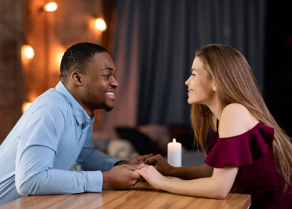 Romantyczna randka. Loving międzyrasowy para siedzi przy stole w restauracji, trzymając się za ręce — Zdjęcie stockowe