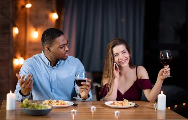Kvinna pratar på mobiltelefon under romantisk dejt, sitter bredvid arg pojkvän — Stockfoto