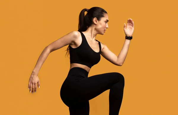 Jovencita corriendo y ejercitándose aislada sobre fondo naranja — Foto de Stock