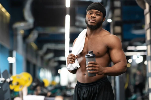 Shirtless black bodybuilder with water and towel at gym — Stock Fotó