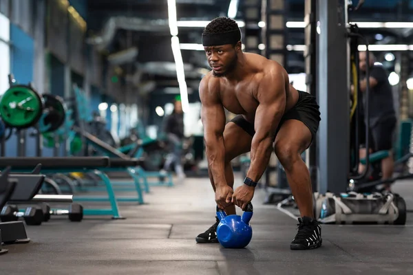 Muscular sem camisa fisiculturista exercitando com kettlebell no ginásio — Fotografia de Stock