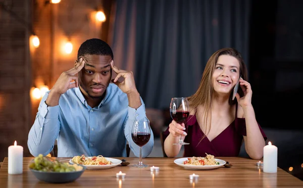 Verveeld man zitten op date naast zijn vriendin praten op mobiele telefoon — Stockfoto