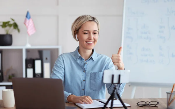 Fröhliche Lehrerin erteilt Online-Englischunterricht von zu Hause aus, zeigt Daumen-hoch-Geste und empfiehlt Sprachschule — Stockfoto