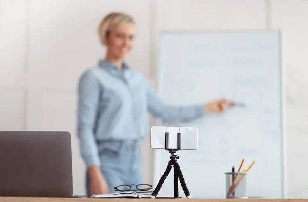 Tutora dando lecciones en línea desde casa, enfoque selectivo del teléfono inteligente en la mesa, espacio para copiar —  Fotos de Stock