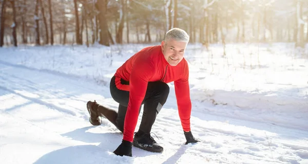 Actividades de invierno al aire libre. Maduro deportista preparándose para correr maratón en carretera nevada en frío día soleado, panorama —  Fotos de Stock