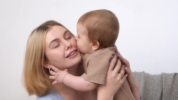 Jonge moeder spelen met haar baby, baby zoenen moeders wang, tijd doorbrengen met elkaar, slow motion — Stockvideo