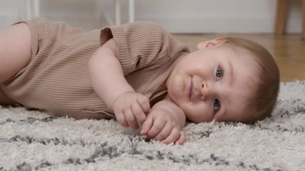 Feliz jogo. Bebê bonito descansando no chão, depois ligando o estômago e rindo, câmera lenta — Vídeo de Stock