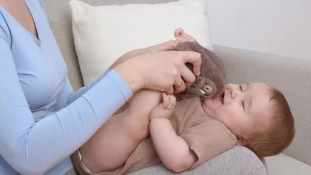 Час грати. Щаслива дитина лежить на колінах матерів, мама грає з немовлям, повільний рух — стокове відео