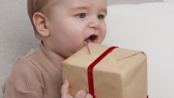 Primo regalo. Bambino carino che gioca con scatola regalo avvolta, mani battenti, rallentatore — Video Stock