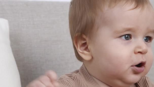 かわいいの肖像6ヶ月赤ちゃんはソファに座って、感情的に見て、遅い動き — ストック動画