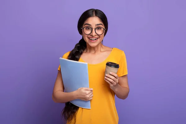 Χαρούμενη Ινδή φοιτήτρια που φοράει γυαλιά κρατώντας σημειωματάριο και καφέ — Φωτογραφία Αρχείου