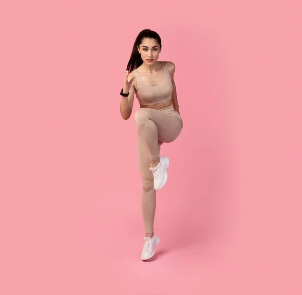 Jovem mulher correndo e exercendo isolado em fundo rosa — Fotografia de Stock