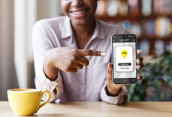 Cropped view of African American woman pointing at cellphone with mobile taxi application at city cafe — Stock Photo, Image