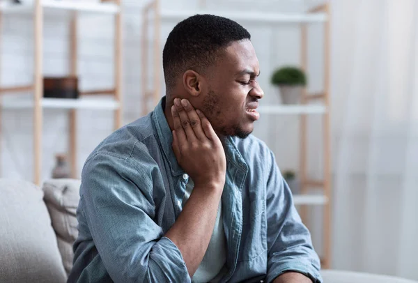 Afrikaanse Guy Massaging Aching Neck Lijden van pijn thuis — Stockfoto