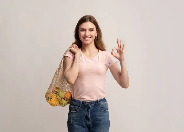 Эко-шопинг. Улыбающаяся женщина держит веревку многоразовый мешок с органическими фруктами — стоковое фото