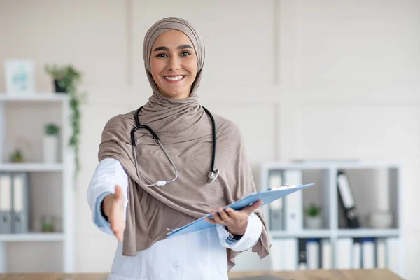 Tıbbi klasörle tesettürlü mutlu kadın doktor birini selamlıyor — Stok fotoğraf