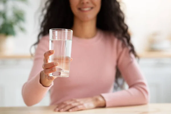 Bebida saudável. Senhora sorrindo irreconhecível que oferece o vidro com água mineral na câmera — Fotografia de Stock