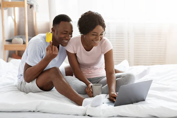 Glücklicher afrikanischer Mann und Frau mit Laptop und Kreditkarte — Stockfoto