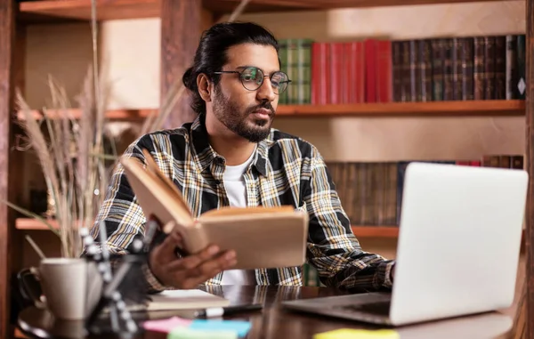 Arab Student Learning Reading Book And Browsing Internet In Library