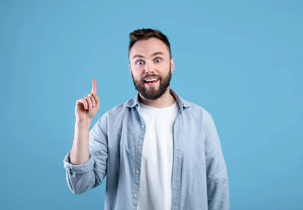 Creatività, idea, ispirazione. Ragazzo fico che punta il dito verso l'alto, gesticolando eureka, vivendo momento AHA su sfondo blu — Foto Stock