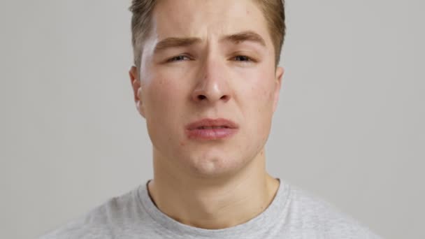 Алергія. Крупним планом молодий чоловік чхає і дме носом з паперовою тканиною, повільний рух — стокове відео