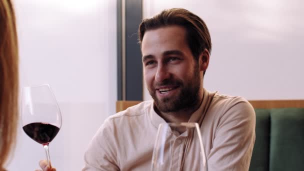 Happy man zeggen toast en klinkende wijnglazen met zijn vriendin, genieten van romantische date in cafe, slow motion — Stockvideo