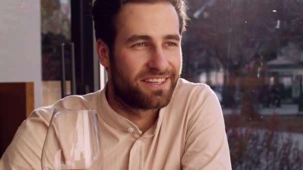 Joven hombre positivo disfrutando de una cita romántica en la cafetería, brindando por su novia con una copa de vino, retrato de cerca — Vídeos de Stock