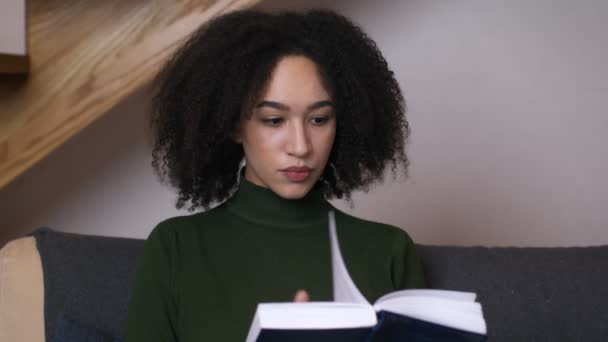 Close up portrait of young black woman reading book and thinking about useful information, slow motion — Stock Video