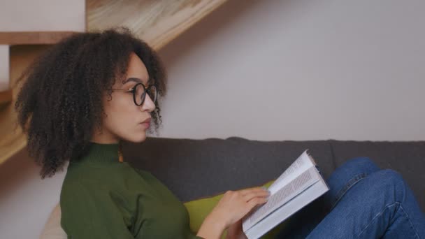 Perfil retrato de jovem afro-americana em óculos lendo livro e pensamento, vista lateral, câmera lenta — Vídeo de Stock