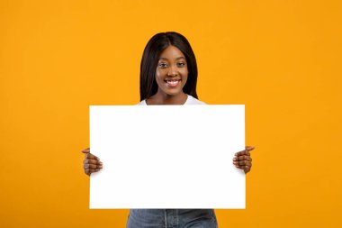 Gülümseyen siyah kadın reklam için boş tahtayı tutuyor.